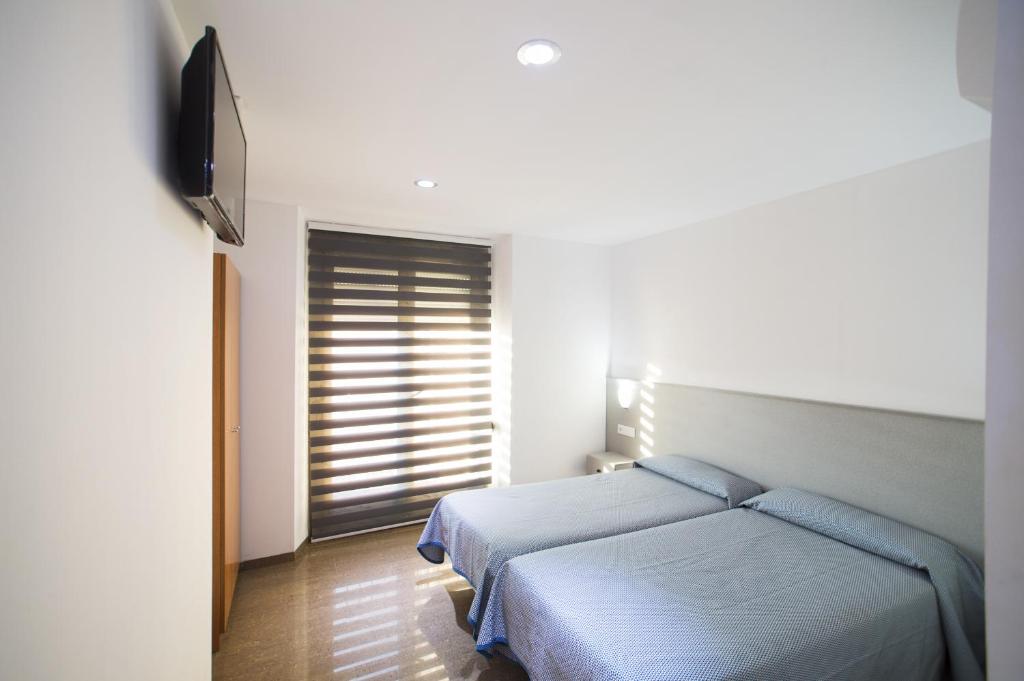 a bedroom with a bed and a flat screen tv at Hostal Drassanes in Barcelona