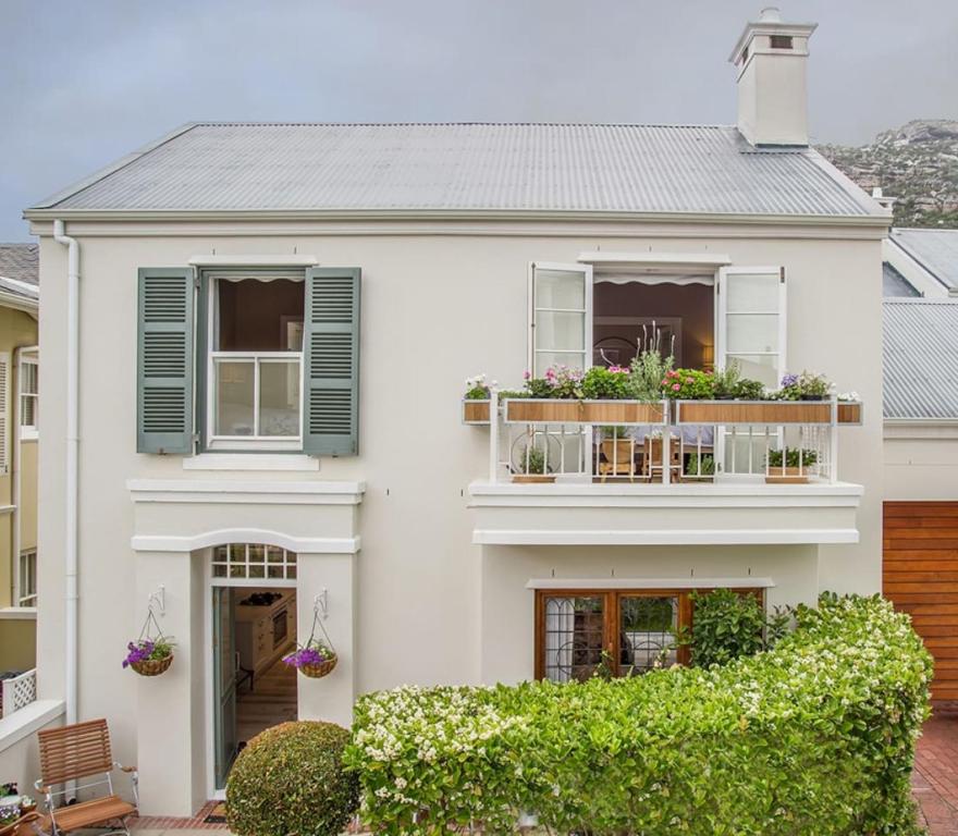 una casa blanca con persianas verdes y un balcón en Charming Coastal Townhouse at The Majestic, en Ciudad del Cabo
