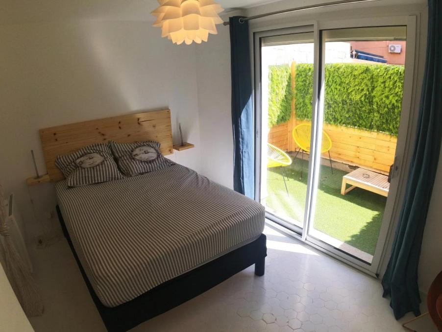 une chambre avec un lit et une porte coulissante en verre dans l'établissement T2 rénové à 50m de la mer, à Canet