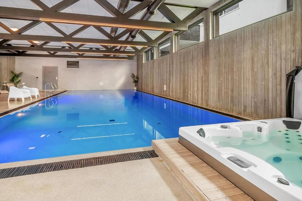 a large swimming pool with a bath tub in a room at Åros Modern Apartment in Kristiansand