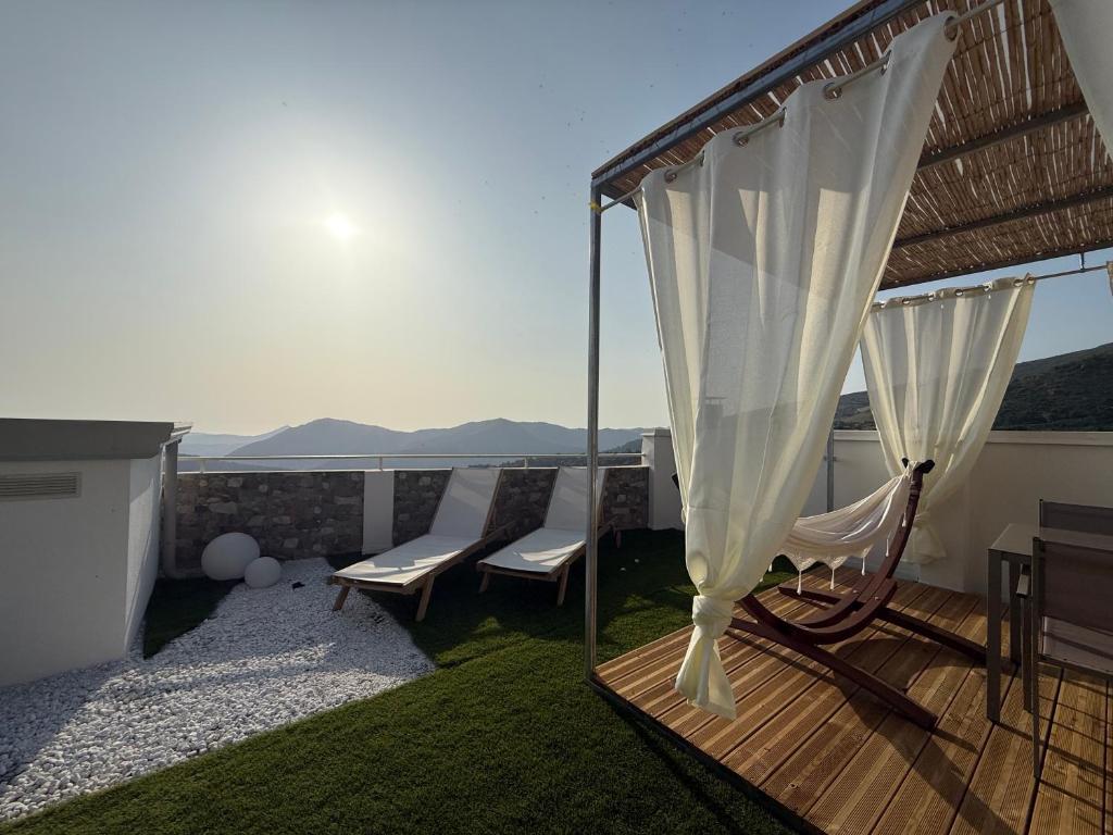 a balcony with two chairs and a white curtain at Umbertos Rooms in Jerzu
