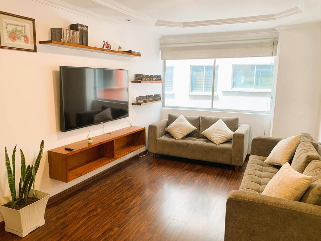 a living room with two couches and a flat screen tv at San Diego Suites Confort, Vista & Estacionamiento en Cuenca in Cuenca