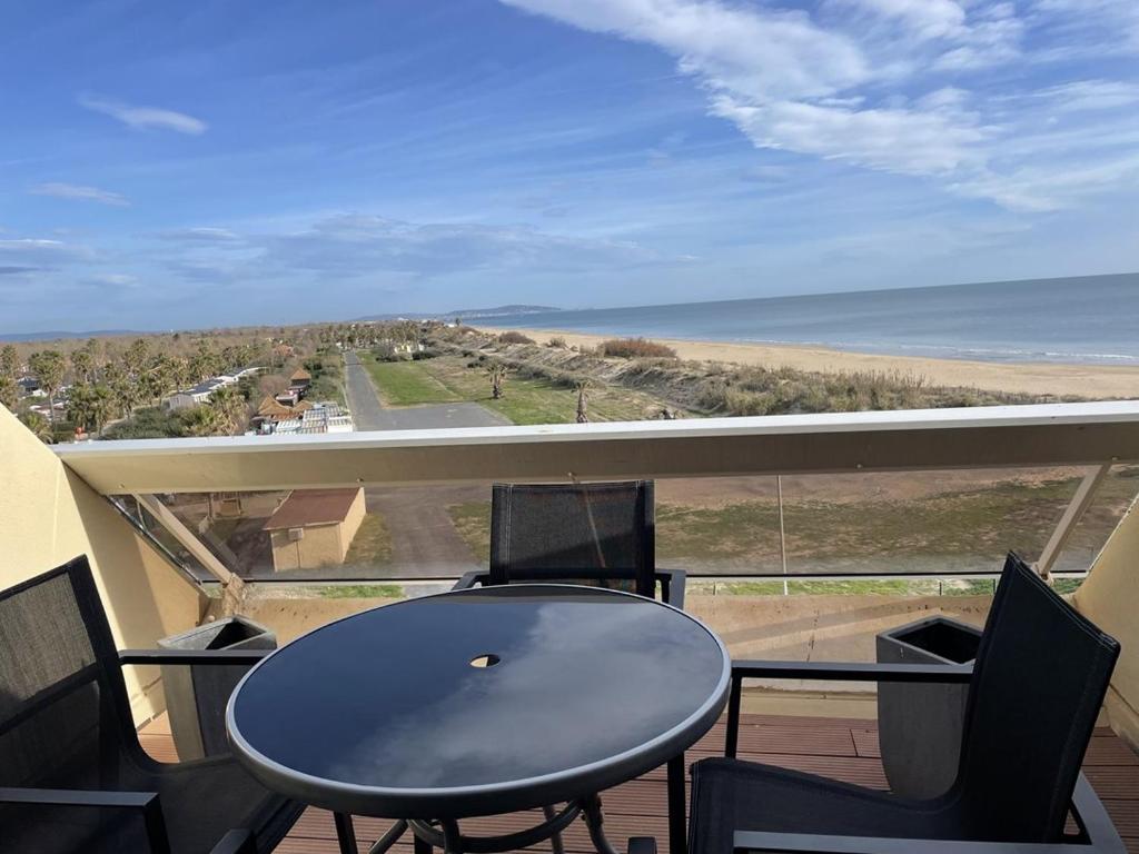 une table et des chaises sur un balcon avec vue sur l'océan dans l'établissement Studio Héliopolis AB 414 - 2 personnes, au Cap d'Agde