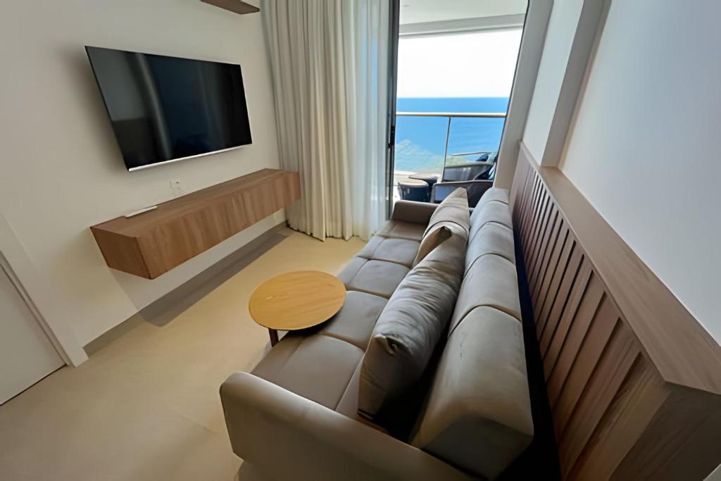 a living room with a couch and a television at UNU 1108 Beach Class Ondina: Vista Mar, Piscina e+ in Salvador