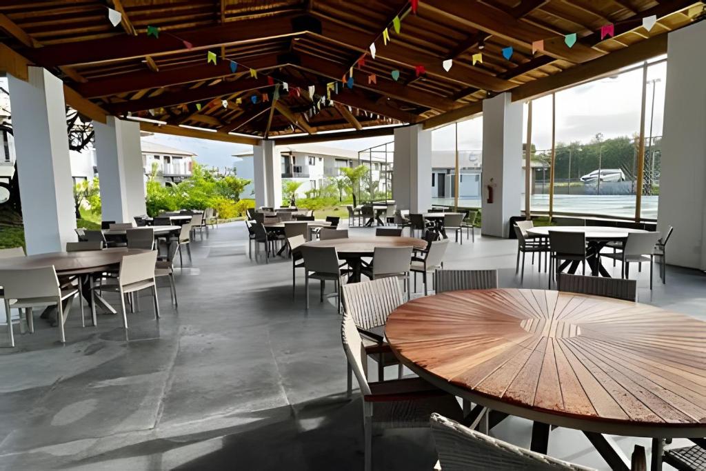 a restaurant with tables and chairs and windows at UNU 204 Studio Praia do Forte: Wifi, Piscina e + in Mata de Sao Joao