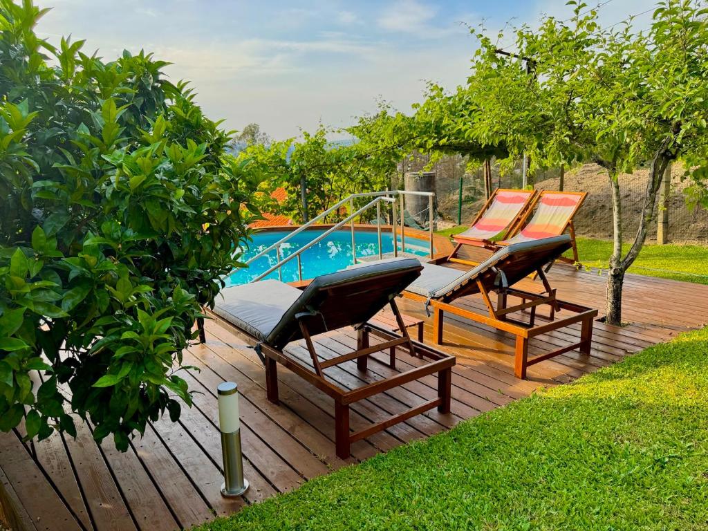 a deck with two chairs and a swimming pool at Quintinha da Oliveira in Marco de Canaveses