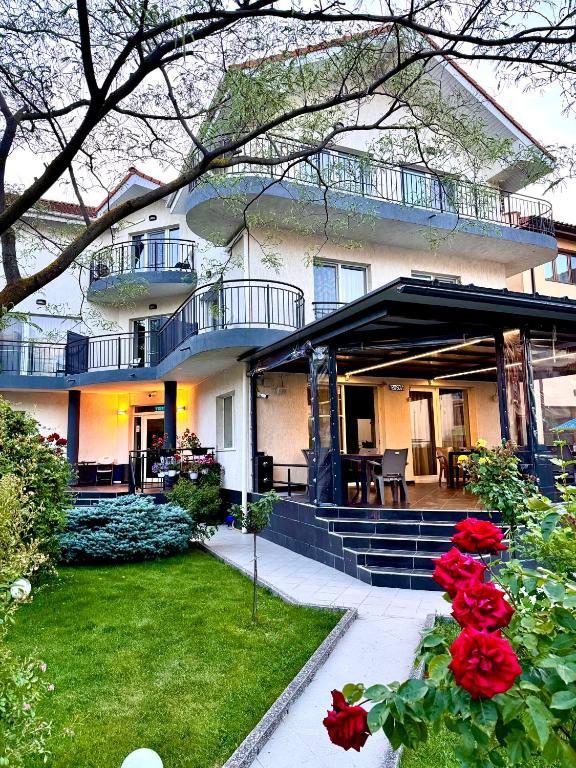 a large house with a yard with red roses at Casa Servus in Mamaia Sat/Năvodari