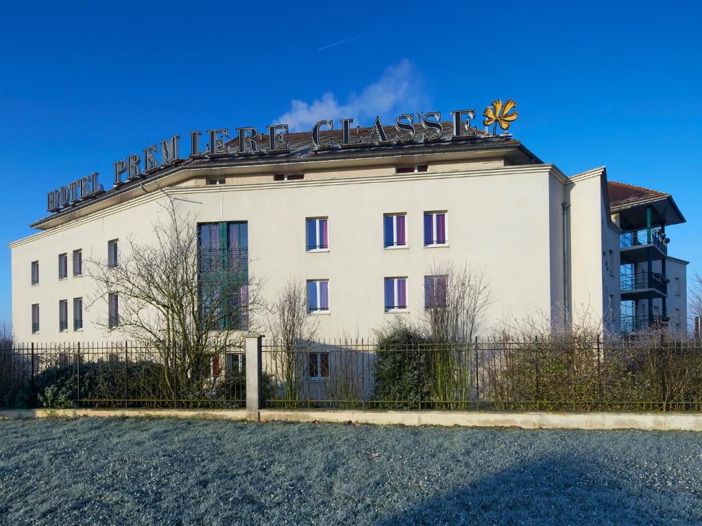 Un bâtiment blanc avec un panneau en haut dans l'établissement Première Classe Marne la Vallée - Bussy Saint Georges, à Bussy-Saint-Georges