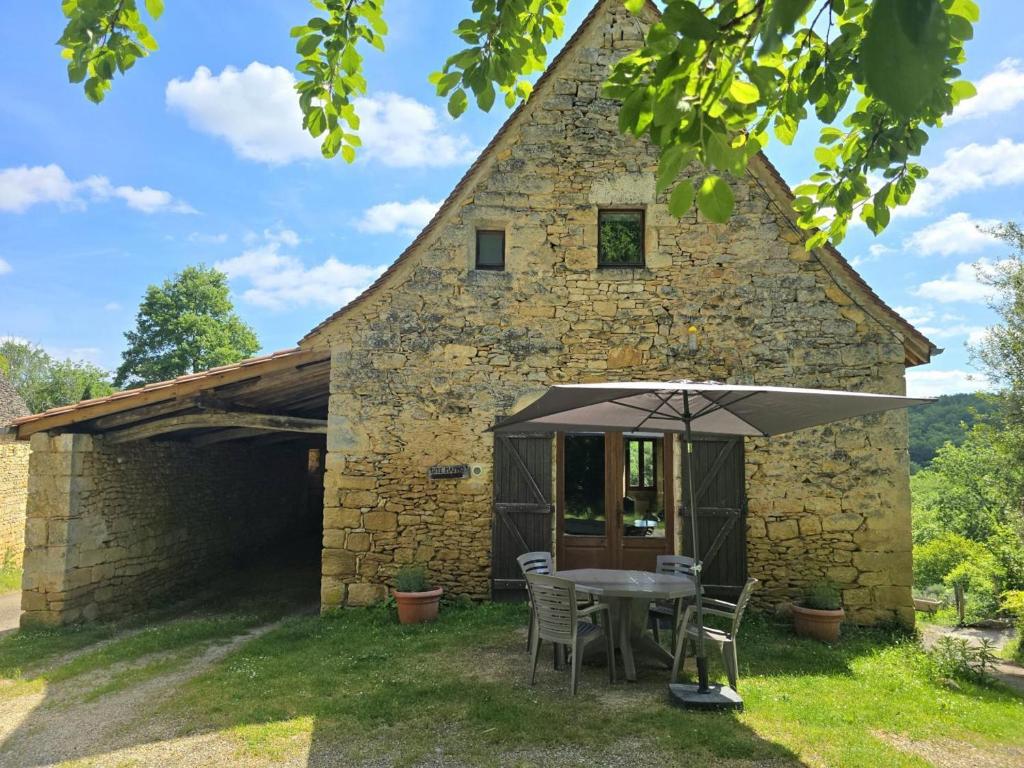 un vecchio edificio in pietra con tavolo e ombrellone di Charmante maison périgourdine avec jardin, cheminée, Wifi et équipements bébé, proche de Sarlat - FR-1-616-130 a Saint-André-dʼAllas