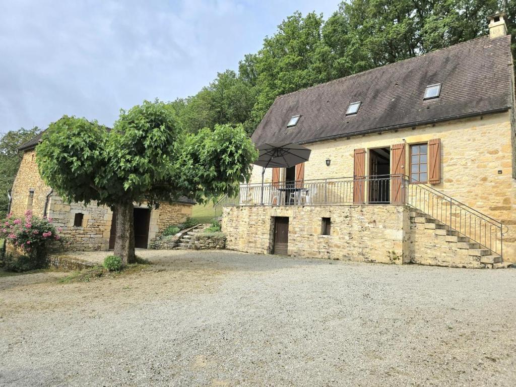 un bâtiment en pierre avec un arbre en face dans l'établissement Maison à Aubas: 2 chambres, animaux admis, parking - FR-1-616-185, à Aubas