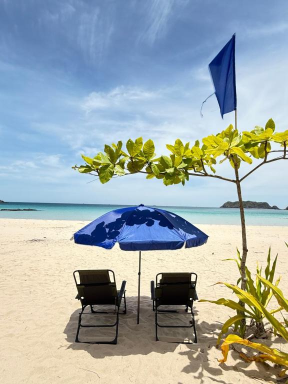 two chairs and an umbrella on a beach at Sea La Vie Cottage in El Nido