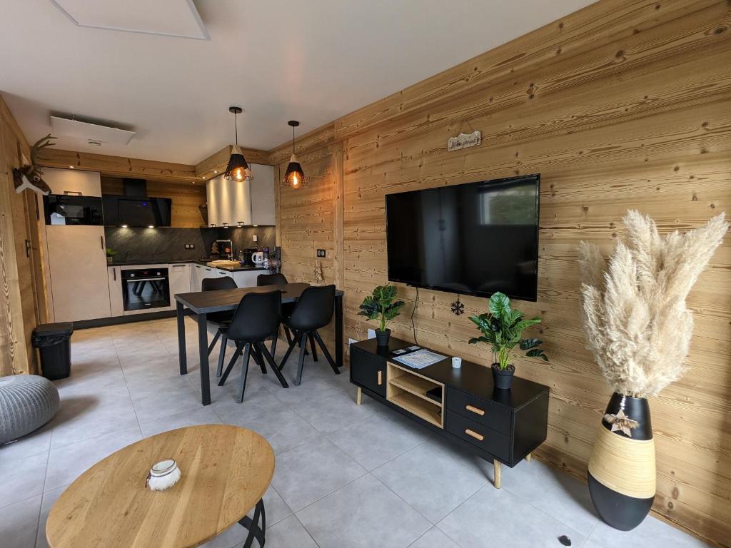- un salon avec une télévision à écran plat sur un mur en bois dans l'établissement Appartement familial proche lac et centre à Gérardmer - 4 pers, animaux admis - FR-1-589-818, à Gérardmer