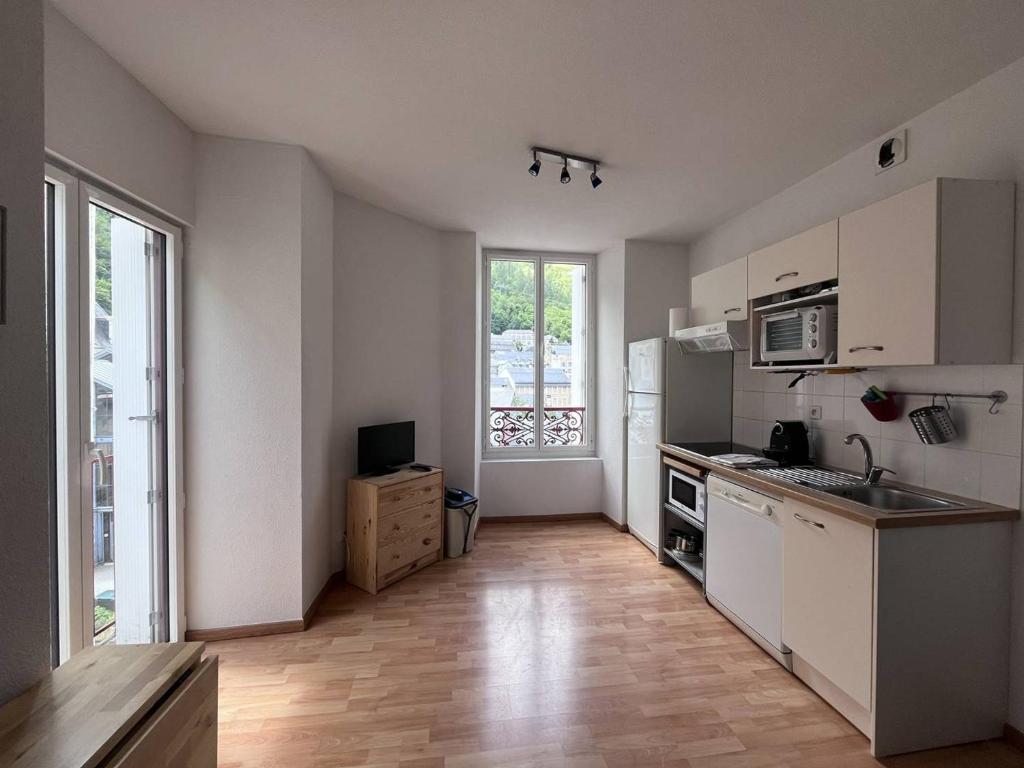 a kitchen with white cabinets and a large window at Appartement central à Cauterets, idéal pour 5 pers, animaux admis - FR-1-812-137 in Cauterets