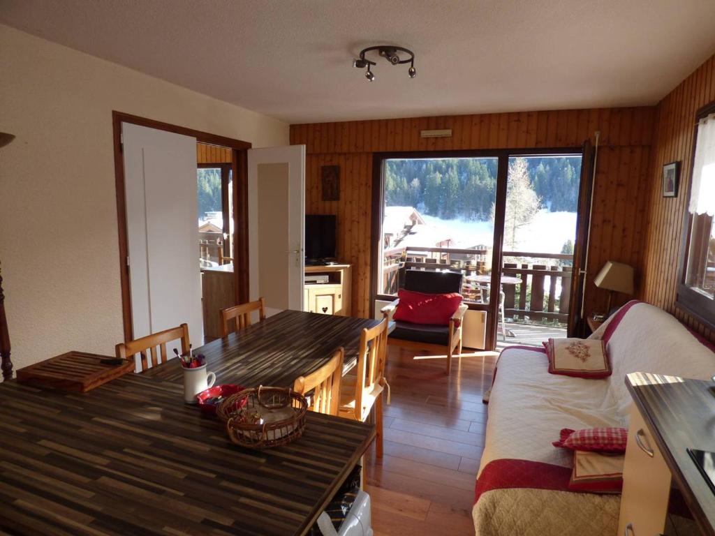 un salon avec une table en bois et une chambre avec un balcon dans l'établissement Appartement lumineux 64m², 6 personnes, vue sur montagnes - FR-1-458-230, au Grand-Bornand