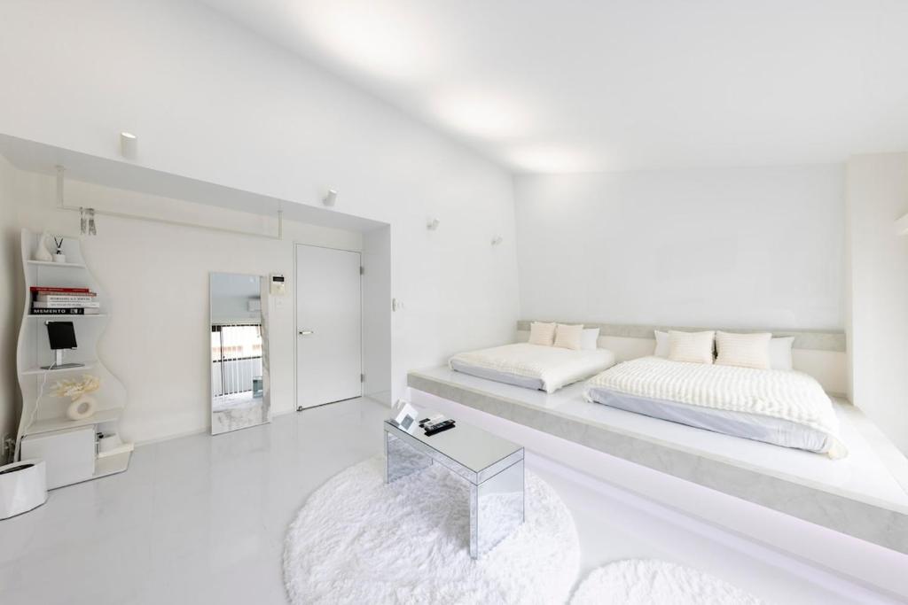 ein weißes Schlafzimmer mit einem großen Bett und einem Tisch in der Unterkunft AMP FLAT Daimyo 702 in Susakiuramachi