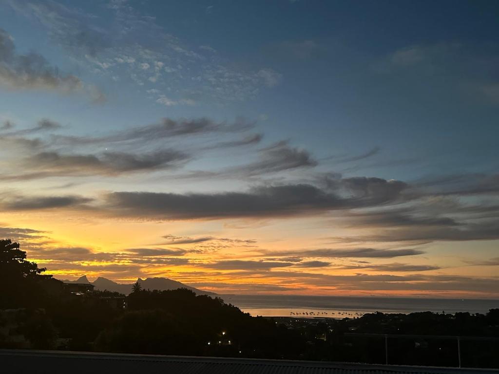 a sunset over the ocean with a cloudy sky at Les Tainas in Faaa