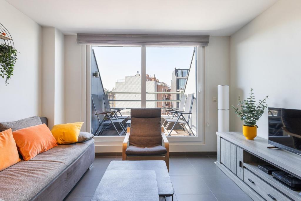 ein Wohnzimmer mit Couch und großem Fenster in der Unterkunft Plaza G14 in Saint-Idesbald