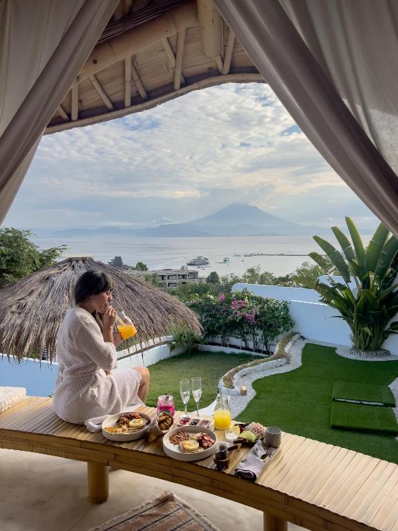 a woman sitting on a table talking on a cell phone at Camanta Penida - Panoramic Sea & Romantic Escape in Nusa Penida