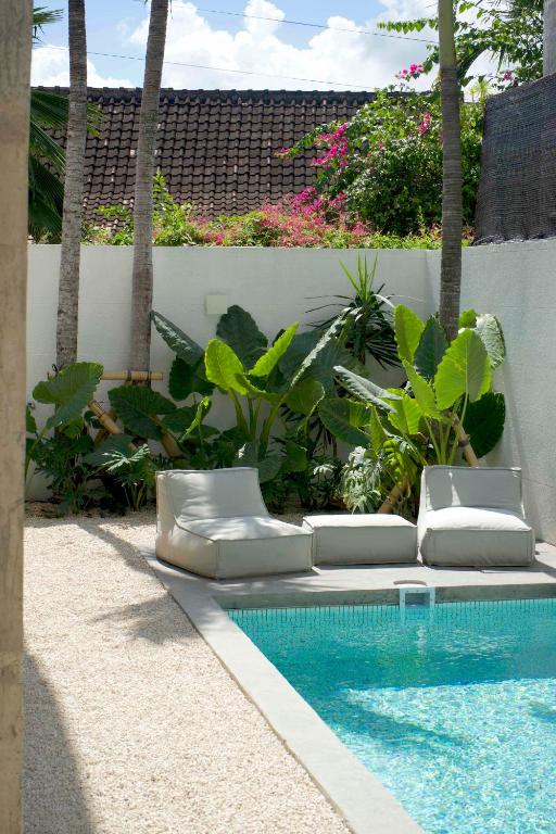 a swimming pool with two chaise lounges and plants at Sojourn in Tumbak Bayuh