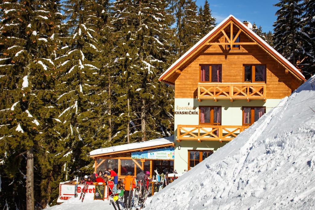 a ski lodge with a group of people standing in the snow at Apartments Kvasničník in Demanovska Dolina