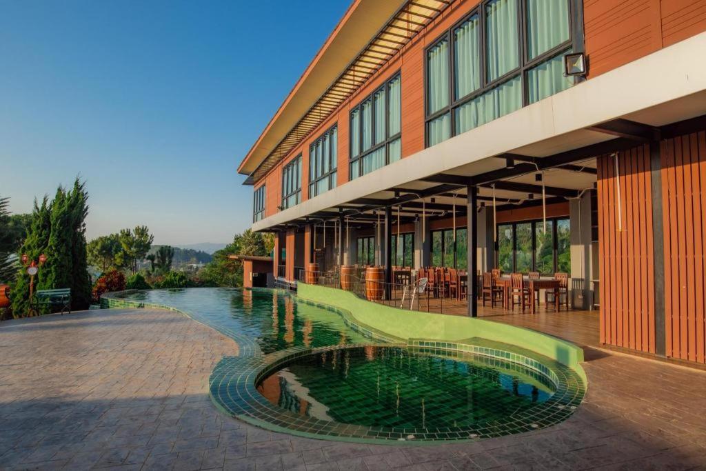 a building with a swimming pool in front of a building at Breeze Hill Resort in Campson