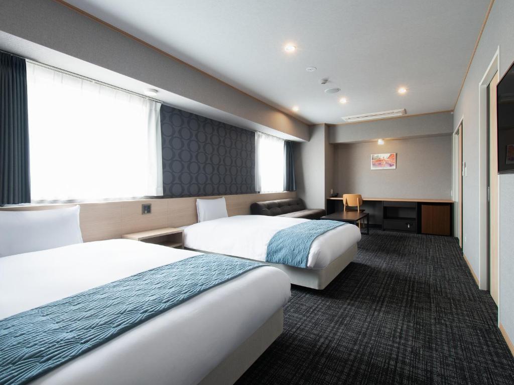 a hotel room with two beds and a desk at Vessel Hotel Hiroshima Peace Blvd in Hiroshima