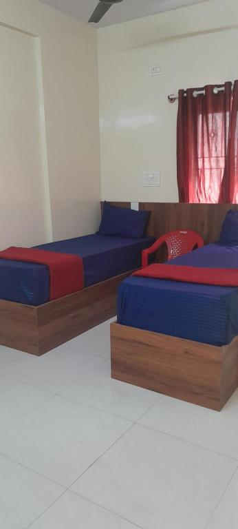 two beds with blue and red sheets in a room at Bhagini Residency Rooms in Bangalore