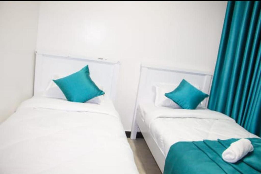 two beds with blue pillows in a room at Cozy Homes in Nakuru