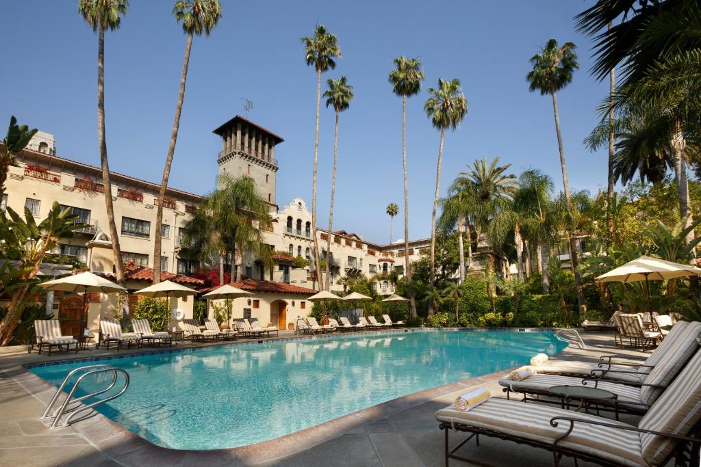 una piscina en un hotel con sillas y palmeras en The Mission Inn Hotel and Spa, en Riverside