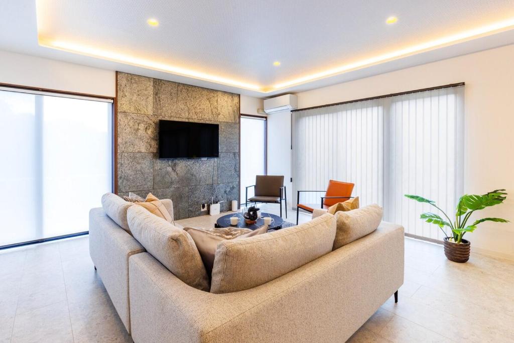 a living room with a large couch and a tv at 最大15名宿泊可 許田ICから車で15分 広々リビングの北部観光におすすめの施設 VILLA de MUI nago in Nago