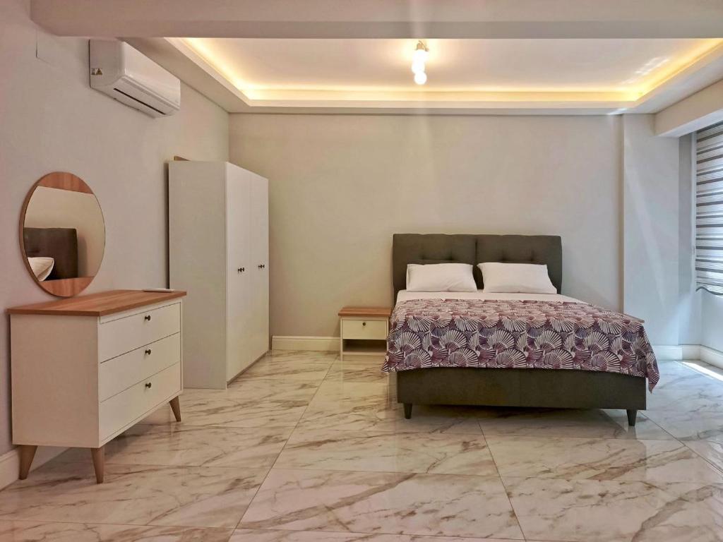een slaapkamer met een bed, een ladekast en een spiegel bij Fethiye central big apartment in Fethiye