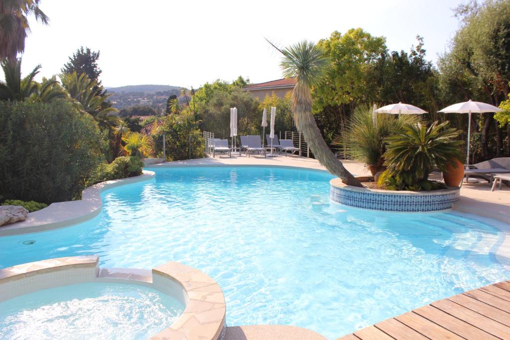 uma grande piscina com uma palmeira e guarda-sol em Royal Cottage em Cassis