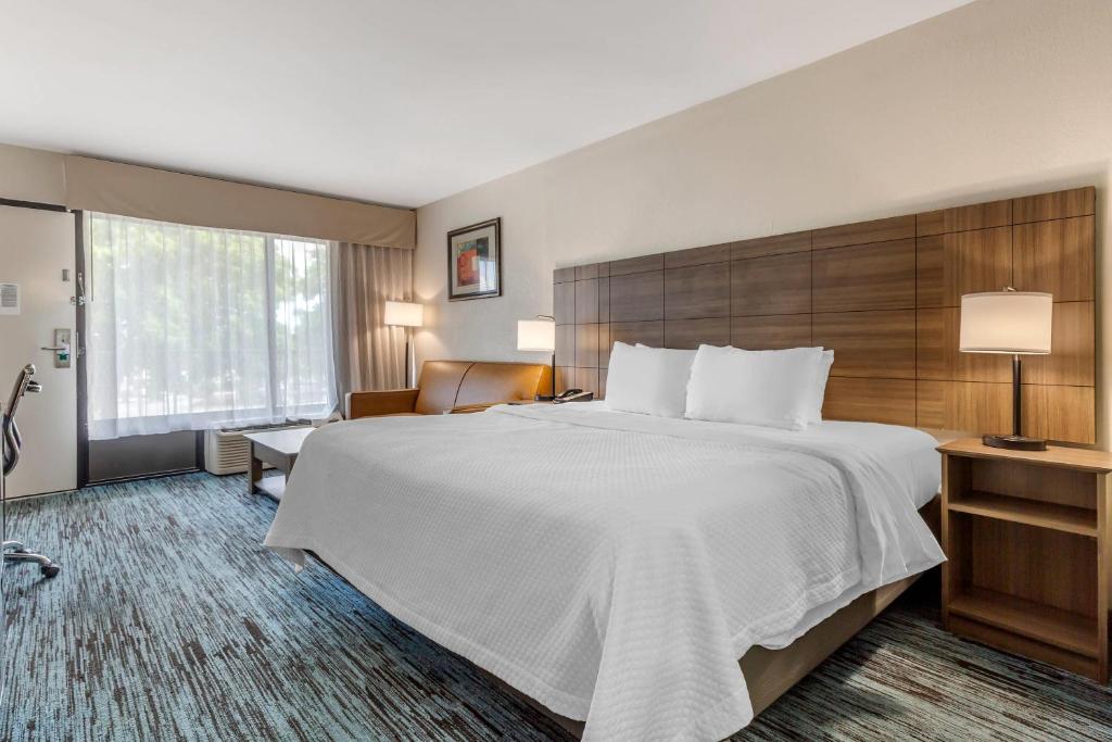 a hotel room with a large bed and a chair at Quality Inn Mount Airy Mayberry in Mount Airy