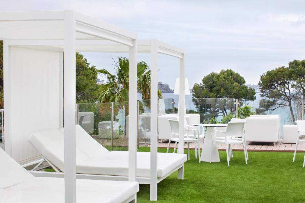 a patio with white furniture and a table and chairs at Morlans Garden in Paguera