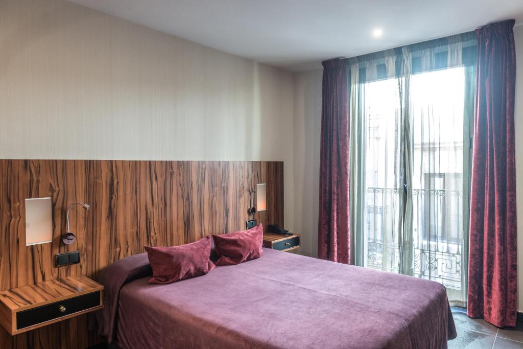 
a bedroom with a large bed and a large window at Hotel California in Barcelona
