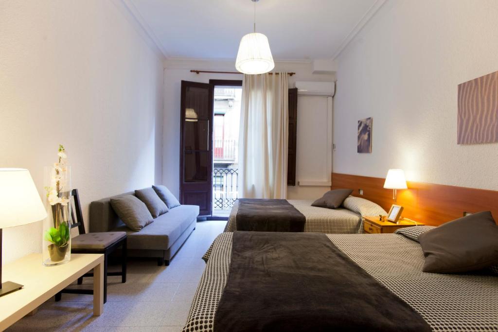 Habitación de hotel con 2 camas y sofá en Hostal Dragonflybcn, en Barcelona