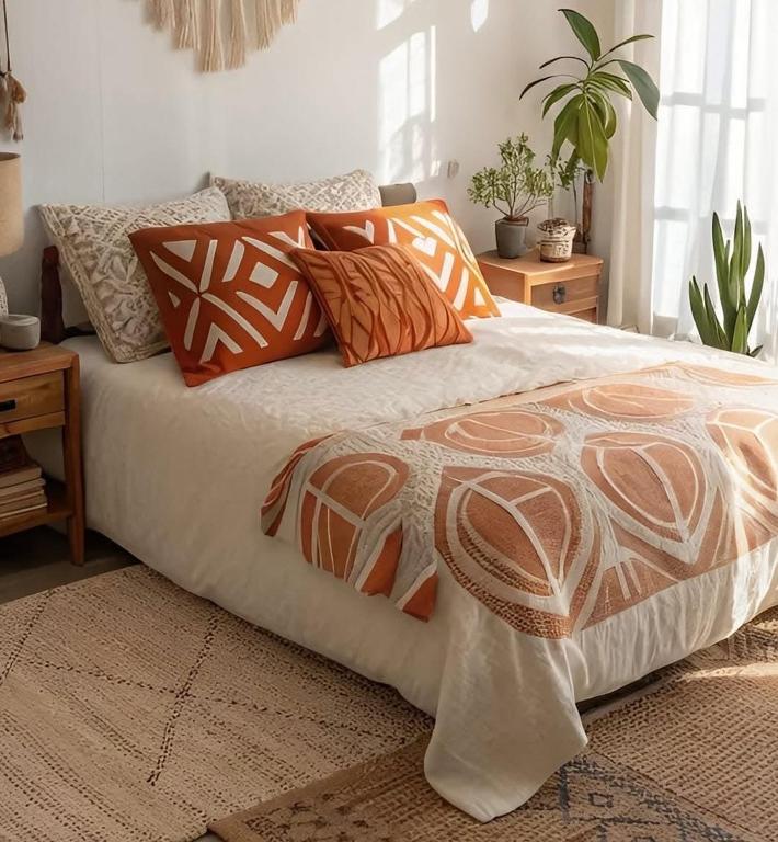 a bed with orange and white blankets and pillows at Fribourg Home in Fribourg