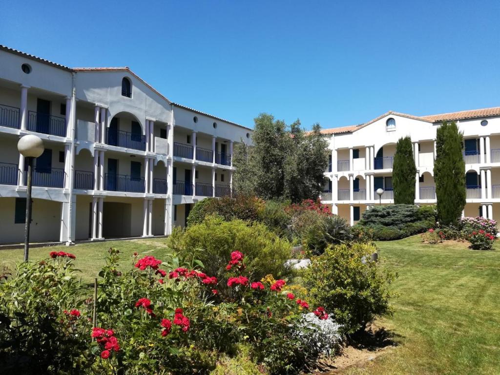 un edificio de apartamentos con flores en el patio en Residence l 'agora, en Vaux-sur-Mer