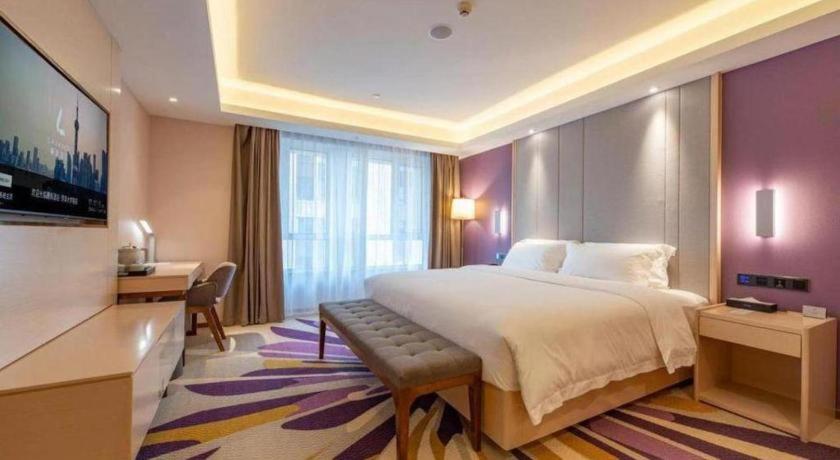 ein Hotelzimmer mit großem Bett und Schreibtisch in der Unterkunft Lavande Hotel Ji'nan Railway Station Long Distance Bus Terminal in Jinan