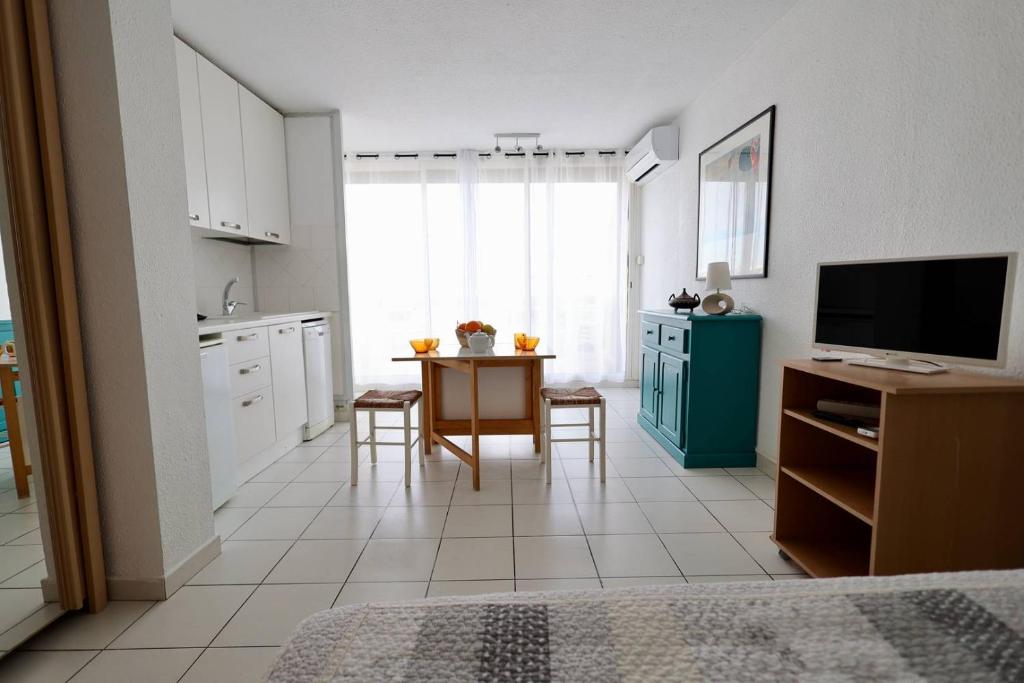 Cette chambre comprend une cuisine avec une table et une télévision. dans l'établissement Studio Héliopolis D 51 - 4 personnes, au Cap d'Agde