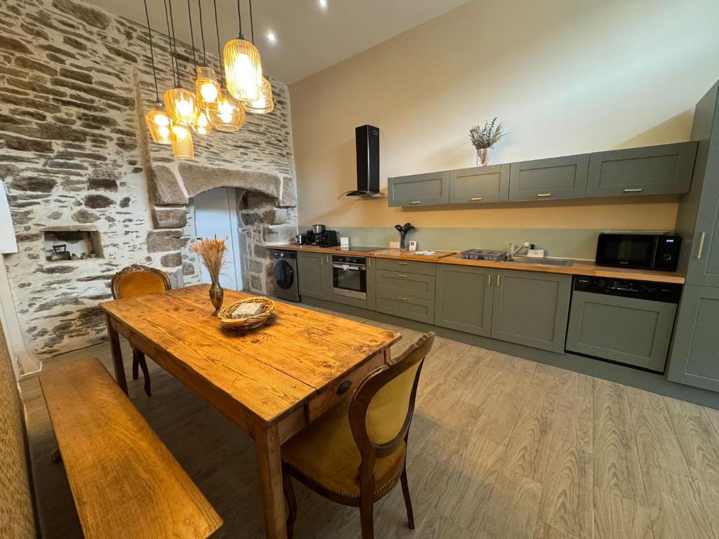 a kitchen with a wooden table and a stone wall at Appartement, terrasse de plain-pied in Plounéventer
