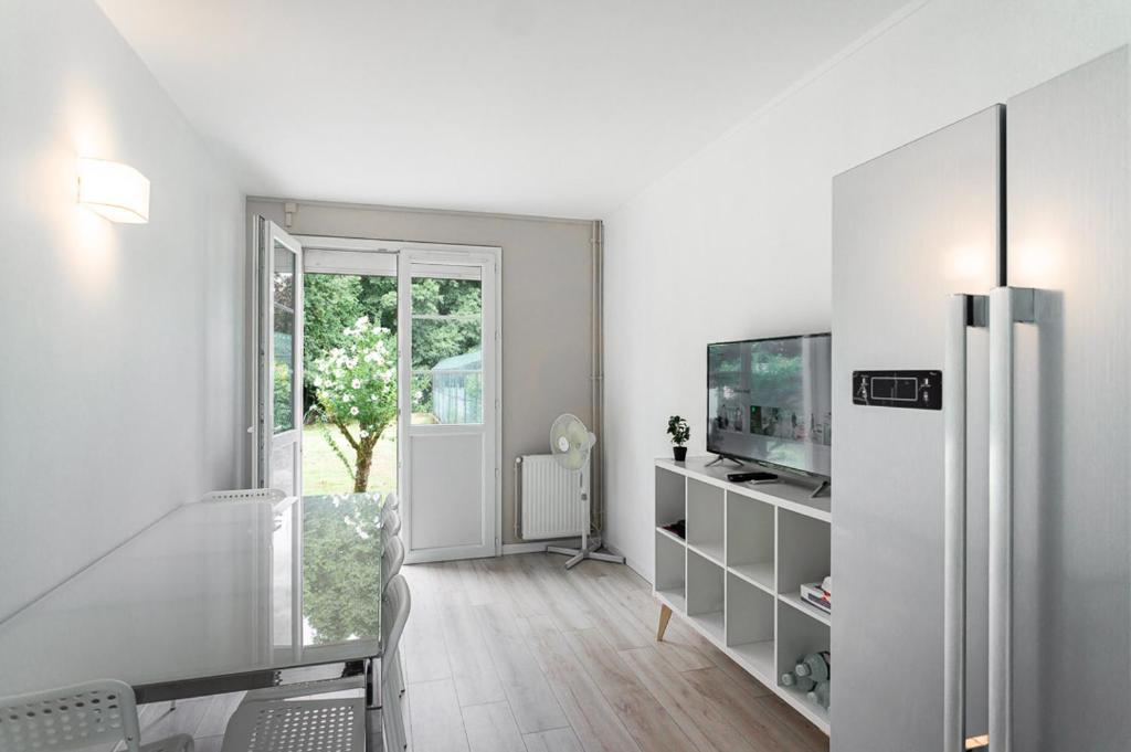 un salon blanc avec une télévision et une porte coulissante en verre dans l'établissement Maison meublé avec jardin, à Talence