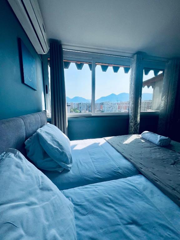 a bedroom with two beds and a large window at Rajs Apartment in Tirana