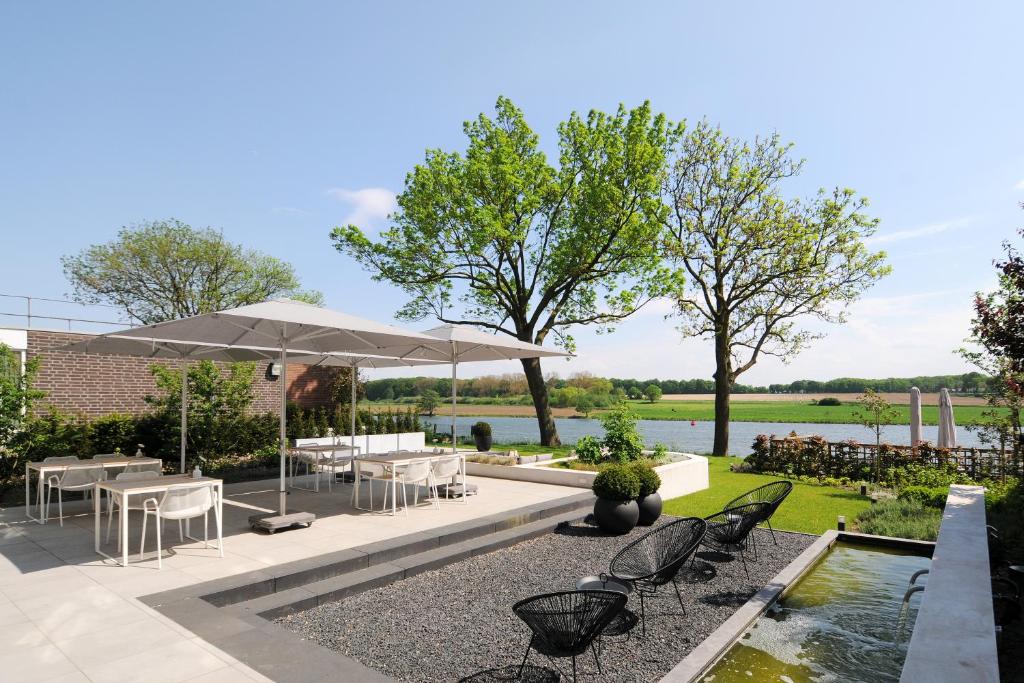 a patio with chairs and an umbrella and a pond at Het Raadhuys - design B&B in Kessel