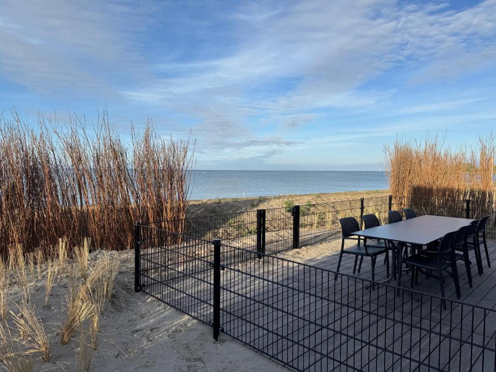 a table and chairs on the beach with the ocean at Enkhuizer Strand BeachHouse Panoramadeck mit Zaun Nr 415 in Enkhuizen