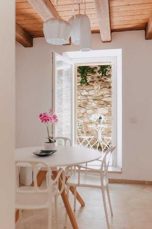 un comedor blanco con mesa, sillas y ventana en Charme in Centro with private parking, en Ascoli Piceno