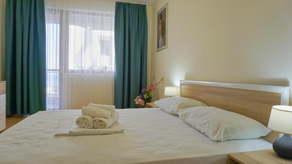 a bedroom with a large white bed with towels on it at Byala Vista Beach Apartments D - Бяла Виста Бийч Апартментс Д in Byala