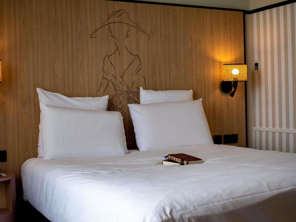 a large white bed with a book on top of it at Mercure Granville Le Grand Large in Granville