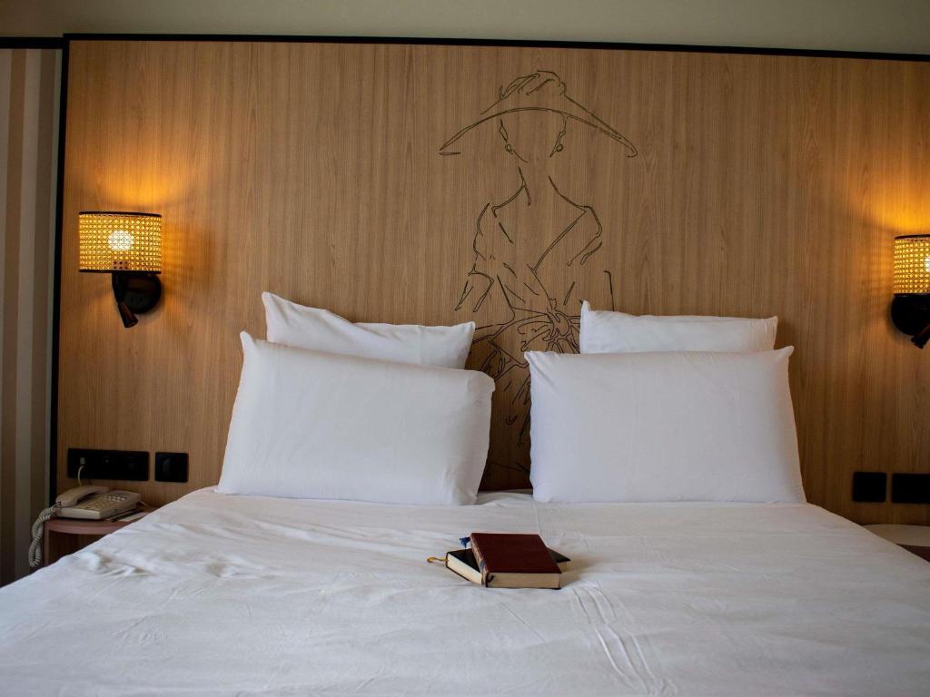a book sitting on top of a bed with pillows at Mercure Granville Le Grand Large in Granville