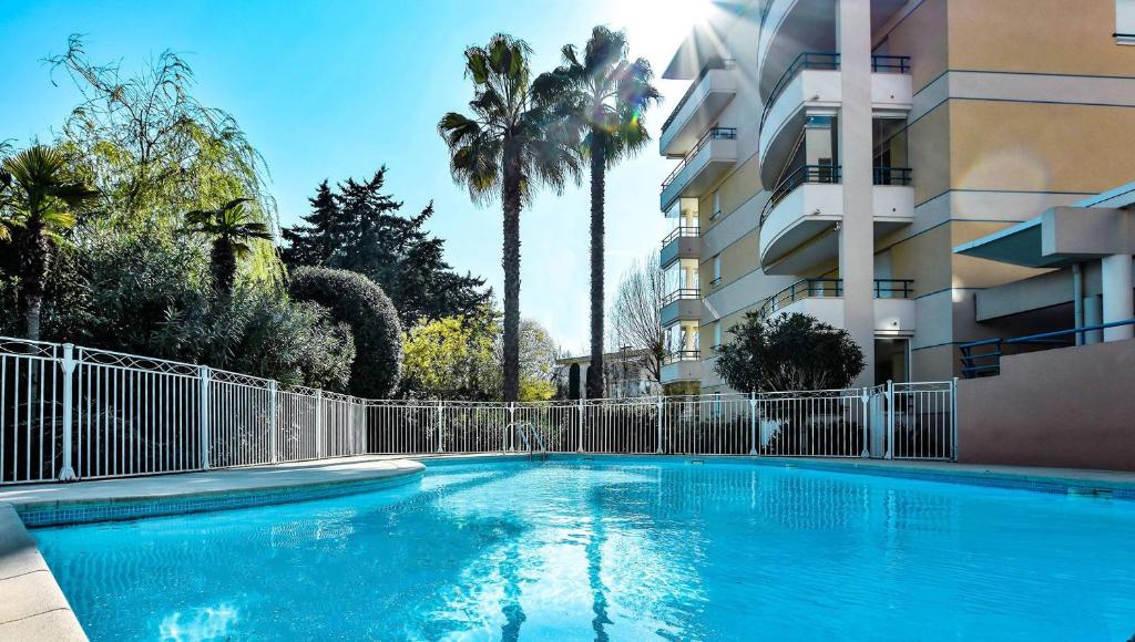 une grande piscine bleue à côté d'un immeuble dans l'établissement Soleil & sable-Fréjus appt 4 pers-Classé 3-Clim, à Fréjus